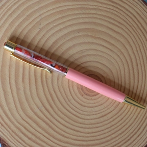 Detail view of pink crystal ballpoint pen with natural red crushed stones and gold accents