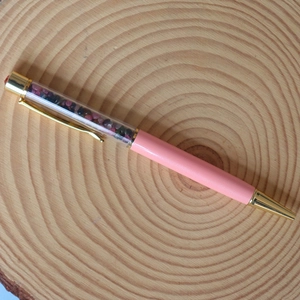 Detail of pink crystal ballpoint pen with gold metal accents and floating gemstone chips