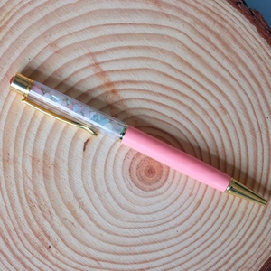 Detailed shot of pink crystal ballpoint pen with gold accents on a wooden background