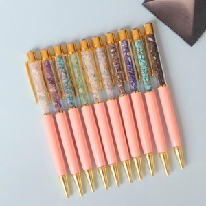 Set of 10 pink crystal ballpoint pens with colorful gemstones on a blue background