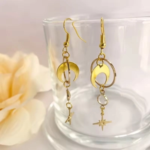 Bohemian gold star and moon drop earrings with crystal accents hanging on glass
