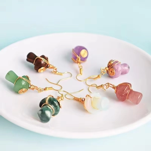 Handmade stone mushroom dangle earrings set with gold wire wrap on a white plate