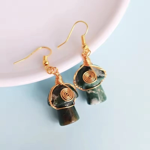 Close-up of handmade wire-wrapped green crystal mushroom earrings with golden hooks