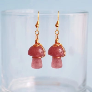 Detail of handmade mushroom earrings with red quartz stones and gold wire wrap craft