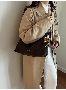 Detail der dunkelbraunen Leder-Tote-Bag mit modischem Schriftzug und Bärenanhänger