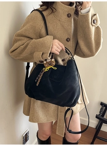 Detailed view of black pleated tote bag with plush bear charm and versatile straps