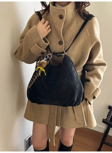 Detail of a large black pleated hobo bag with a cute brown teddy bear pendant