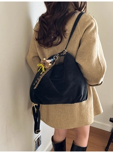 Detail of black matte pleated hobo bag with a cute brown bear charm on the strap