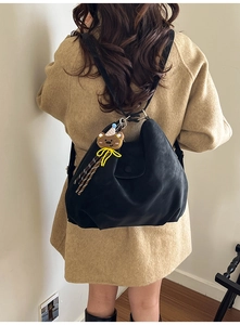 Detail view of large black tote bag with soft pleated texture and brown bear charm
