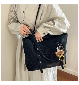 Detail of black matte tote bag with long straps and a cute brown bear charm ornament