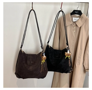 Detail of large tote bags in brown and black with soft leather and cute bear pendant