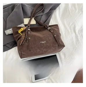 Detail of dark brown vintage faux leather tote bag with tassels and shoulder straps