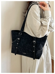 Detail of vintage black tote bag with silver buckle strap and matte leather texture