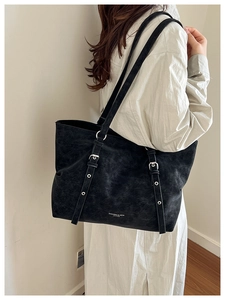 Detail view of large black retro leather tote bag with silver buckles on shoulder model