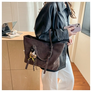Detail of dark brown suede tote bag with side adjustable strap and cute bear charm