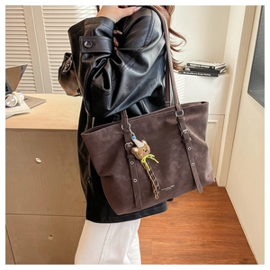 Close-up of brown vintage oversized tote bag with plush bear charm and adjustable strap