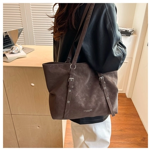 Detail of dark brown suede tote bag with silver buckle strap and debossed logo detail
