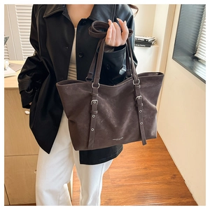 Brown retro tote bag with dual straps and textured faux leather in a minimalist setting