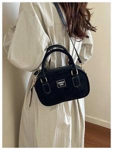 Detail of a black vintage bowling bag with matte leather finish and gold hardware