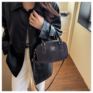 Classic black crossbody bag with logo tag styled on a model in a leather coat