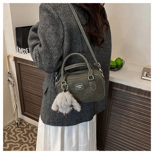 Close-up of vintage bowling bag with plush rabbit charm and adjustable strap