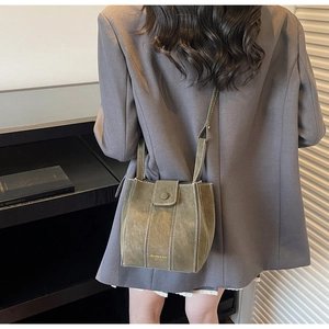 Detail of olive green bucket bag with contrast white stitching and gold logo lettering