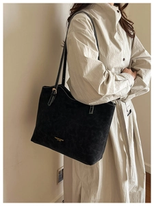 Detailed side view of black tote bag with white stitching and leather texture