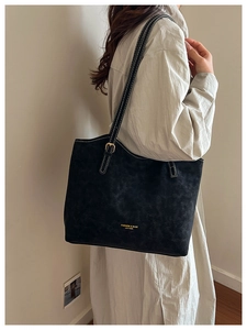 Detail of black tote bag with white stitching and gold hardware on female model