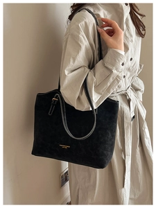Detail of large black tote bag with white contrast stitching and gold text engraving