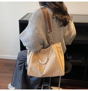 Detail of beige tote bag with decorative pearl chain and premium gold floral pendants