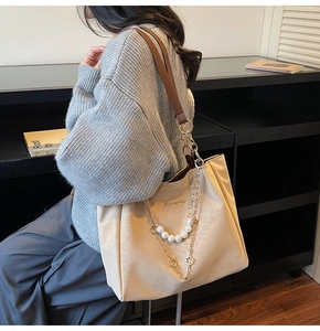 Detail of apricot tote bag featuring gold chain, white pearls and glossy fabric texture
