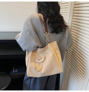 Close-up of beige tote bag with layered pearl and metal flower chain strap detail