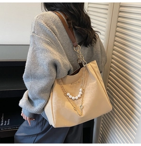 Detail of beige tote bag featuring gold chain, pearl charms, and Sunnycity metal logo