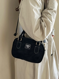 Retro black crossbody bowling bag with white stitching and detachable strap