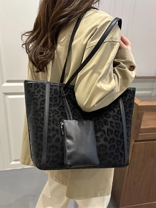 Large leopard print tote bag with mini pouch shown on shoulder in minimalist setting