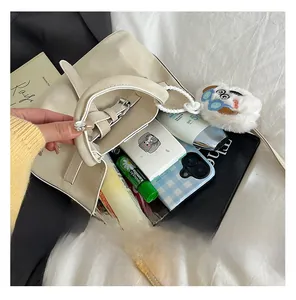 Détail montrant la grande capacité intérieure de ce sac seau en daim crème avec accessoires