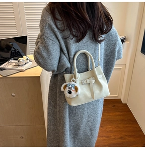 Détail du sac à main crème en cuir avec pendentif en peluche et boucle métallique chic