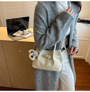 Détail d'un sac à bandoulière en cuir beige orné d'un joli pendentif chien en peluche