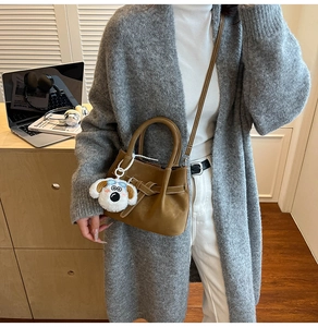Sac bandoulière en similicuir marron mat avec charm peluche porté sur une tenue chic