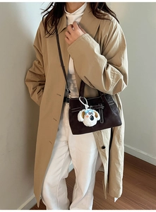 Détail du sac bandoulière en daim marron foncé avec boucle et pendentif chien en peluche