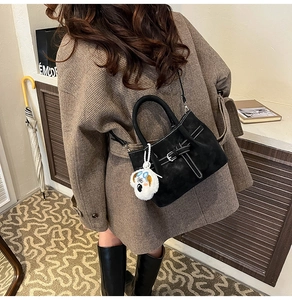 Détail du sac seau en daim noir avec surpiqûres blanches et breloque chien en peluche
