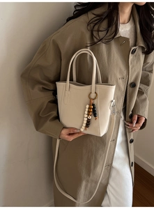 Chic cream white bucket bag with beaded charm and U-shaped stitching detail