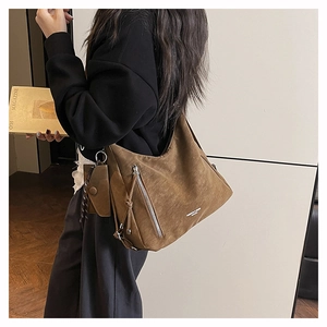 Dettaglio borsa a spalla in camoscio marrone con zip argento e mini pochette appesa