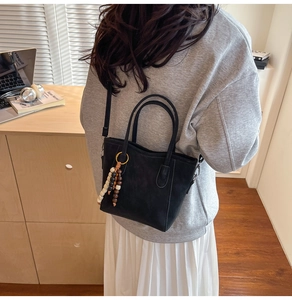 Detail of black matte tote bag featuring stylish tricolor wooden bead pendant decoration