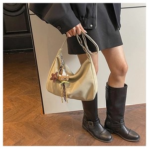 Close-up of a khaki tote bag with a cute bear charm and silver zipper detail