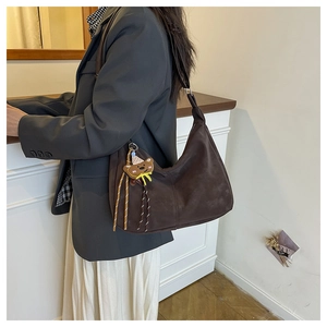 Brown suede hobo bag with a cute bear charm accessory styled on a fashion model