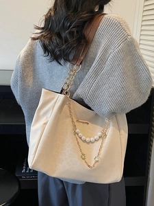 Off-white large tote bag with pearl and gold chain detail on model in minimalist interior