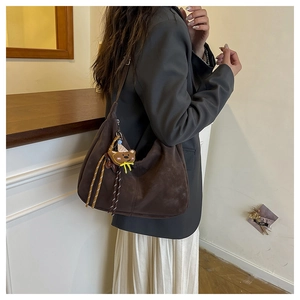 Detail of dark brown suede hobo bag with cute bear charm and woven yellow lanyard
