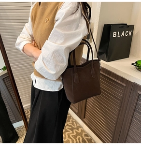 Vue latérale du sac seau en cuir nubuck marron foncé porté en bandoulière en intérieur