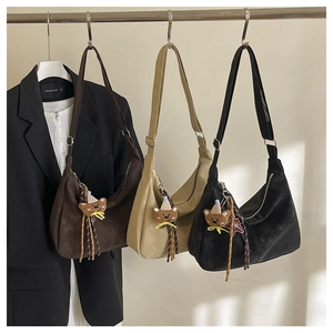 Detailed view of three half-moon hobo bags with bear charms and tassel accents